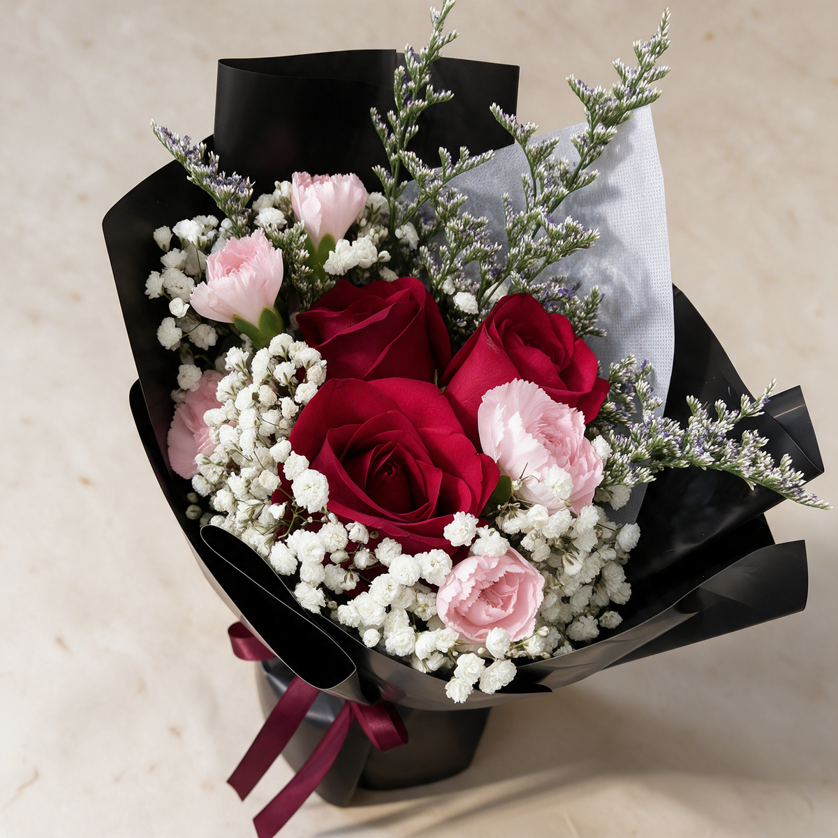 Top view of the Blissful fresh flower bouquet of three red roses with spray carnations, baby’s breath and caspia