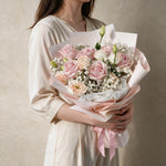 Woman holding the Secret Crush fresh flower bouquet in blush pink wrap