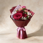 Smitten fresh flower bouquet of three deep red roses with spray carnations, asters and baby’s breath in burgundy wrap