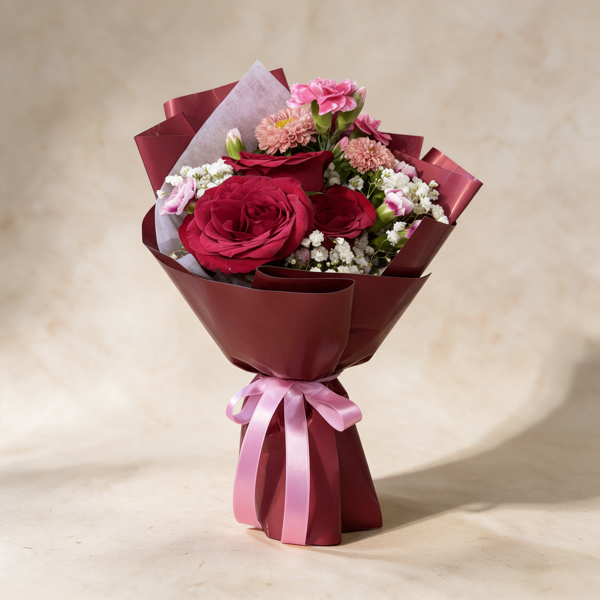 Smitten fresh flower bouquet of three deep red roses with spray carnations, asters and baby’s breath in burgundy wrap