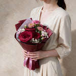 Woman holding the Smitten fresh flower bouquet in burgundy wrap