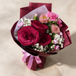 Top view of the Smitten fresh flower bouquet of three deep red roses with spray carnations, asters and baby’s breath