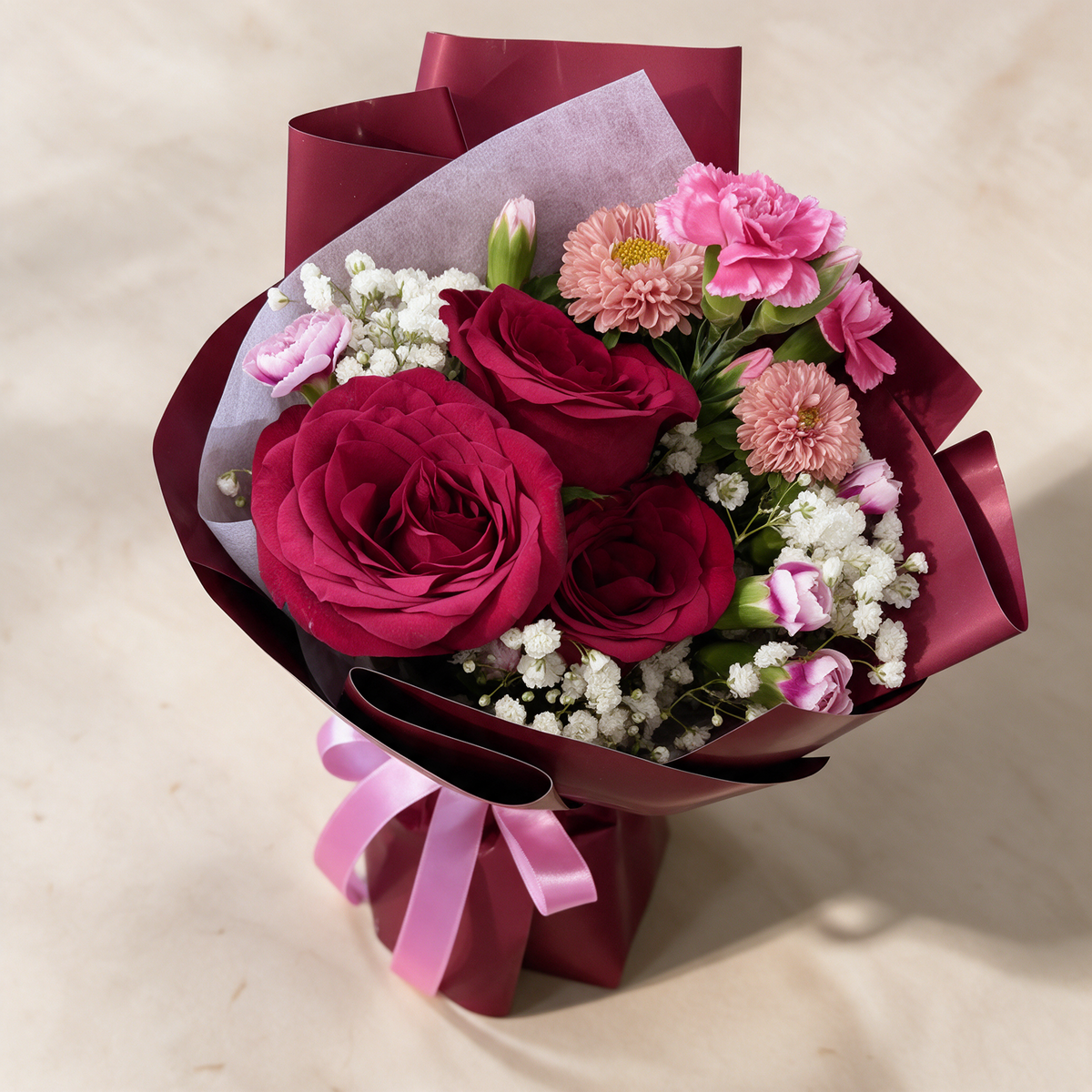 Top view of the Smitten fresh flower bouquet of three deep red roses with spray carnations, asters and baby’s breath
