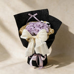 True Affection soap flower bouquet of eight lilac roses and a cosmos in black and gold wrap