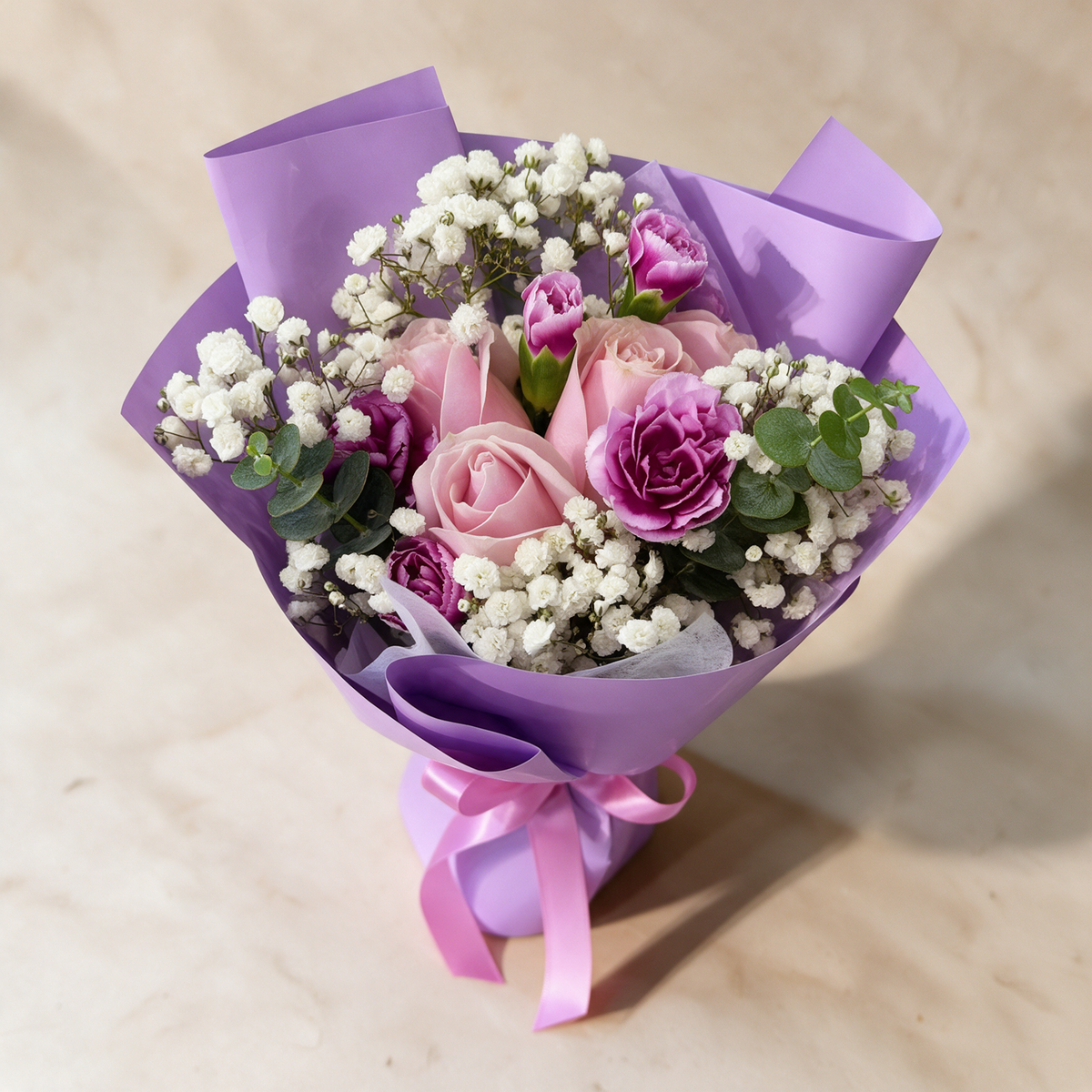 Top view of the Whisper fresh flower bouquet of three pink roses with spray carnations, baby’s breath and eucalyptus