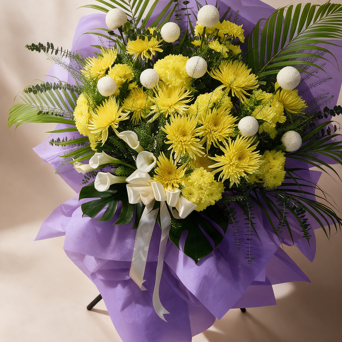 Close-up of the Grace condolence flower stand of yellow chrysanthemums and white calla lilies