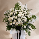 Close-up of the Heavenly condolence flower stand of white roses and ping pong chrysanthemums