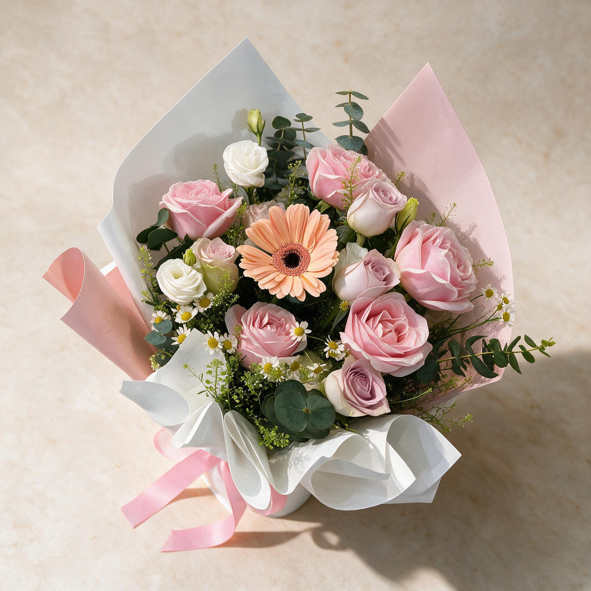 Top view of the Love Story fresh flower bouquet of ten pink roses and a peach daisy with mini daisies, eustoma, eucalyptus and thlaspi green bells