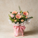 Serendipity fresh flower bouquet of three peach daisies with spray carnations, yellow peacock and eucalyptus with a pink ribbon