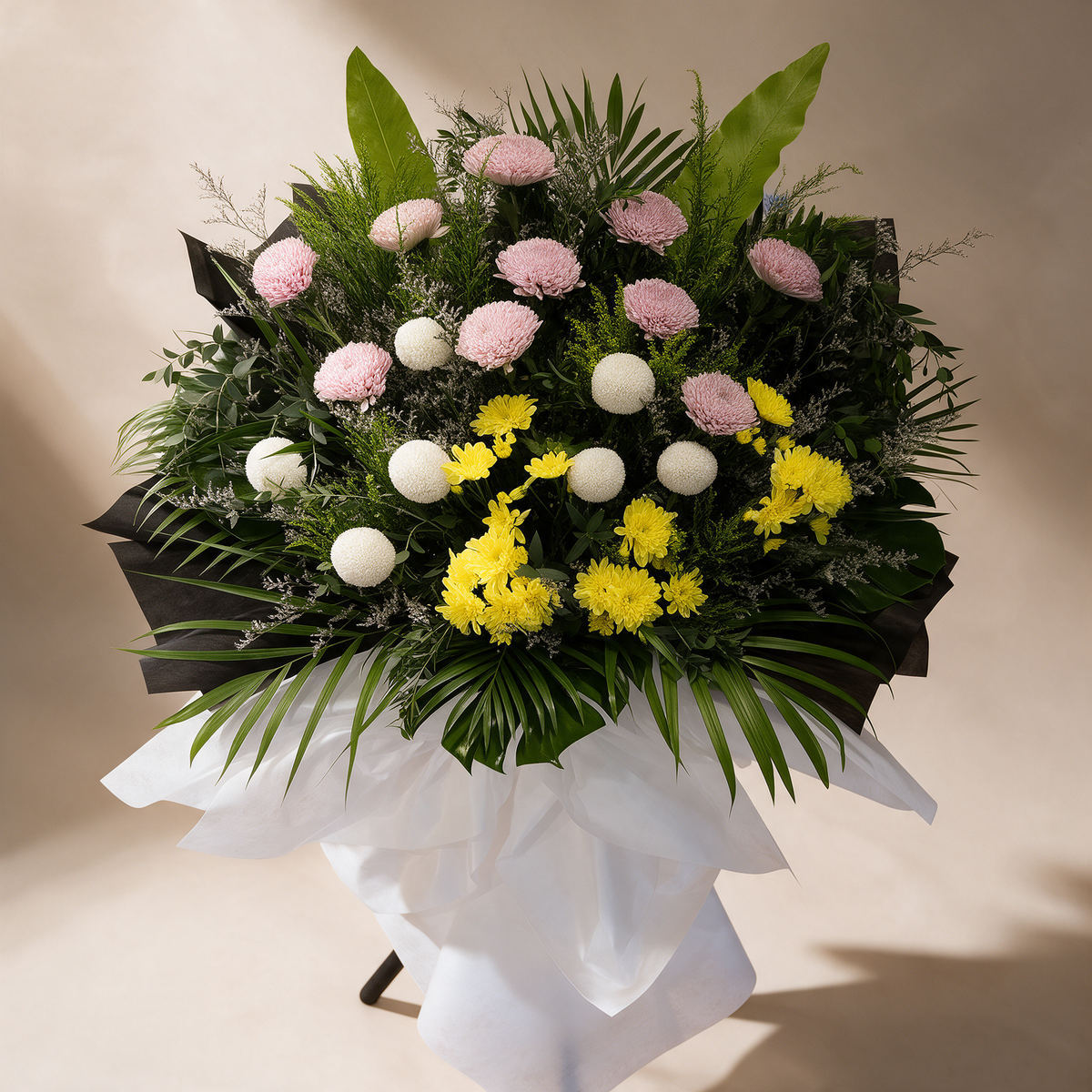 Close-up of the Solace condolence flower stand of white, pink and yellow chrysanthemums