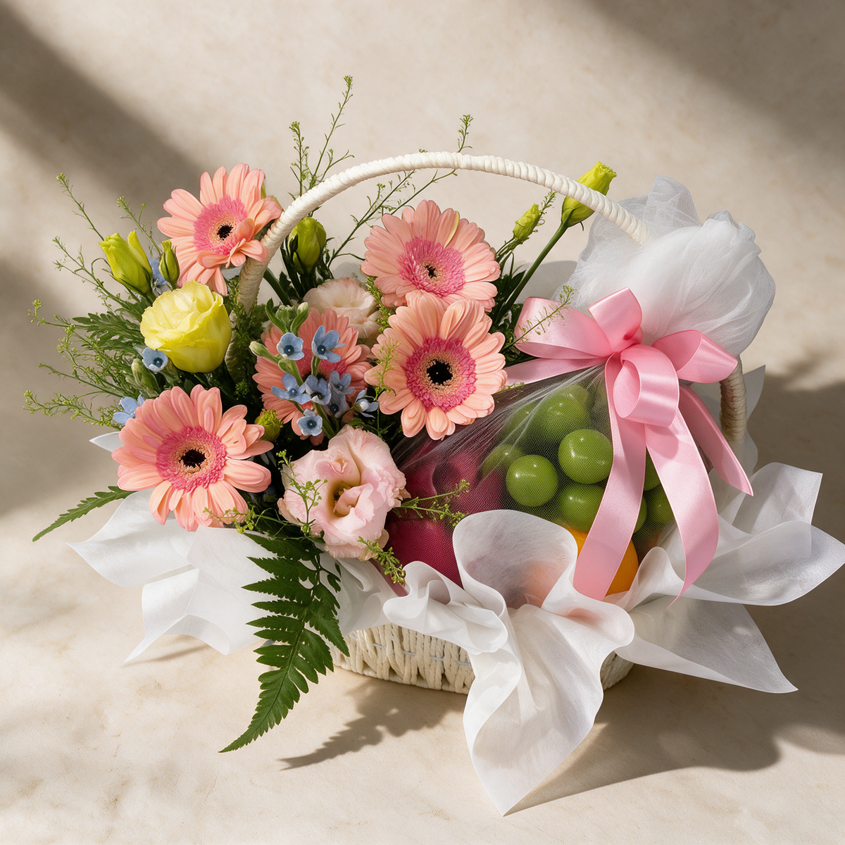 Top view of the Wishful fresh flower and fruit basket of five peach daisies with eustoma and yellow peacock beside fresh seasonal fruit